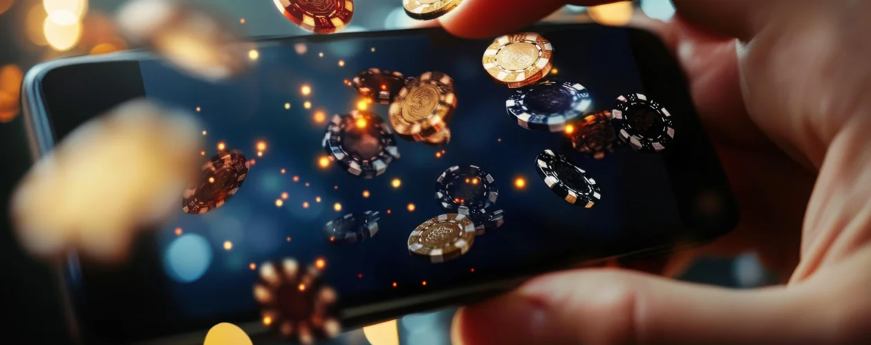 A close-up shot of hands holding a smartphone with gold and black casino chips floating and glowing over the screen.